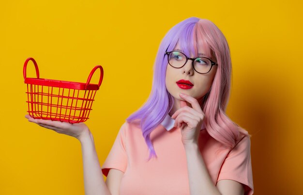 Chica con cabello morado y vestido rosa con cesta roja sobre fondo amarillo