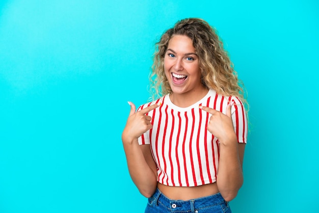 Chica con cabello rizado aislado sobre fondo azul dando un gesto de pulgar hacia arriba