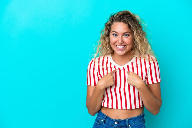 Chica con cabello rizado aislado sobre fondo azul con expresión facial sorpresa