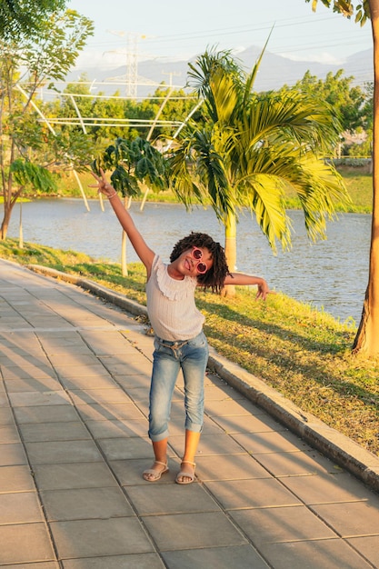 Chica con cabello rizado jugando en el parque en el patio de recreo