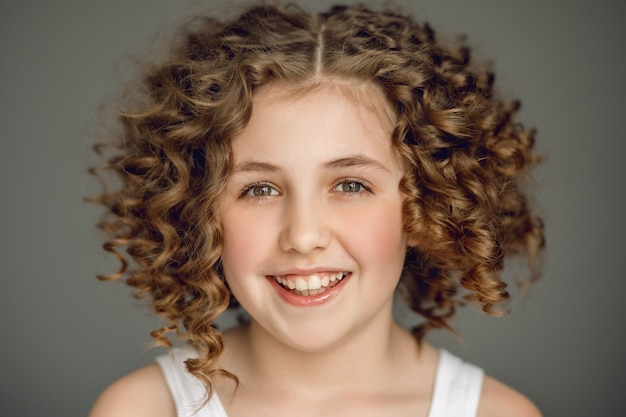 La chica de cabello rizado sonríe maravillosamente, su mirada se dirige directamente al marco.