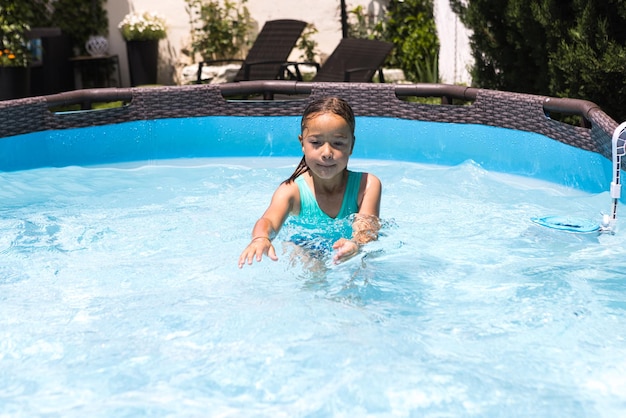 Chica de cabello rubio en una piscina disfrutando en el agua Piscina nadar traje de baño niños verano relajarse resort de vacaciones y concepto de viaje