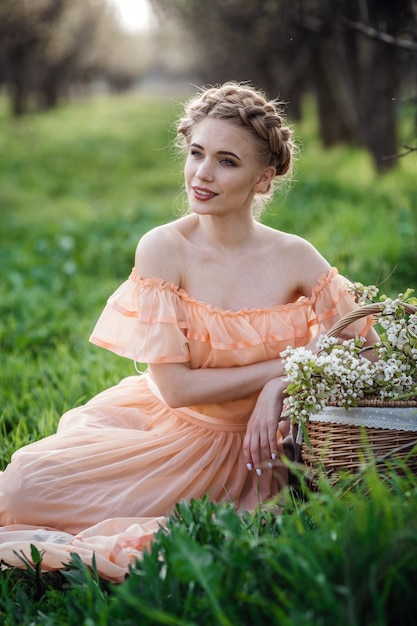 Chica con cabello rubio con un vestido ligero en jardín de flores. concepto de moda femenina de primavera.