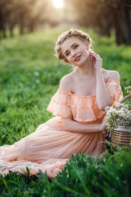 Chica con cabello rubio con un vestido ligero en jardín de flores. concepto de moda femenina de primavera.