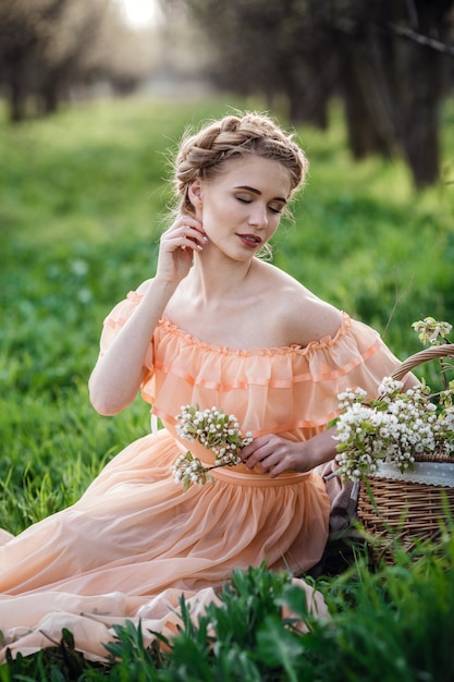 Chica con cabello rubio con un vestido ligero en jardín de flores. concepto de moda femenina de primavera.