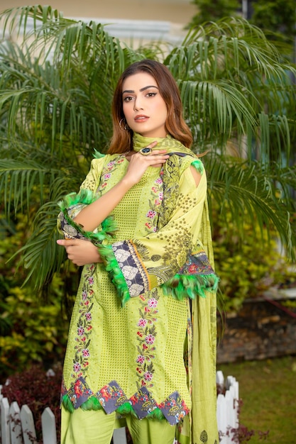 Chica de cabello rubio con vestido verde Desi para sesión de fotos de moda en un jardín