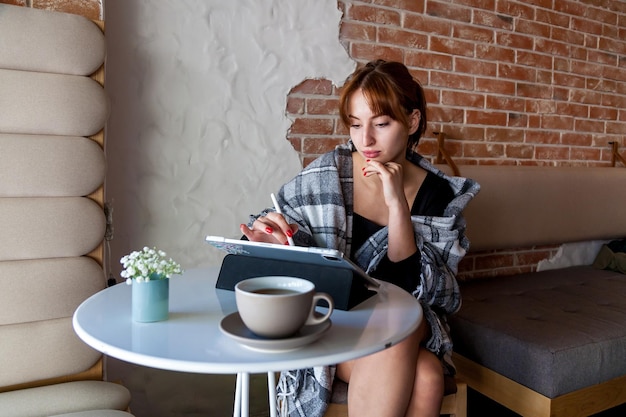 Una chica en un café dibuja con un lápiz en una tableta gráfica