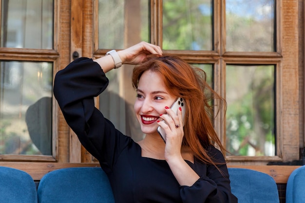 Una chica en un café en una mesa hablando por teléfono