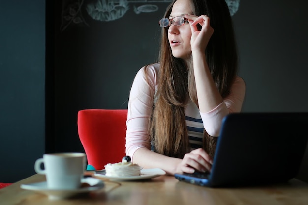 Chica en un café por una taza de café con el cuaderno.