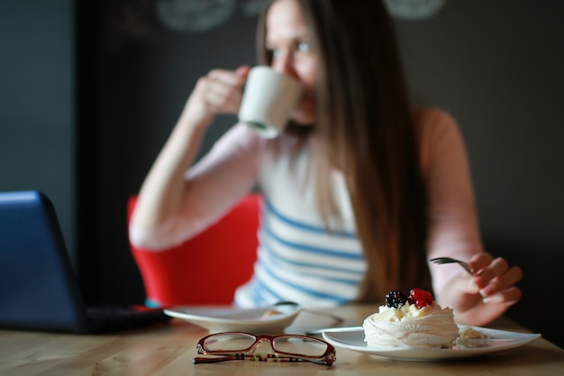 Foto chica en un café para tomar una taza de café con el portátil