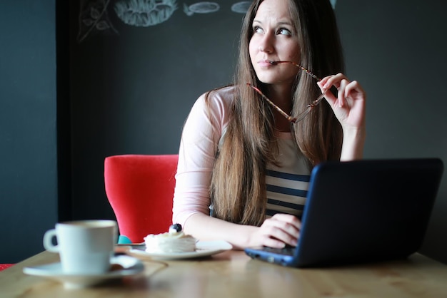 Chica en un café para tomar una taza de café con el portátil