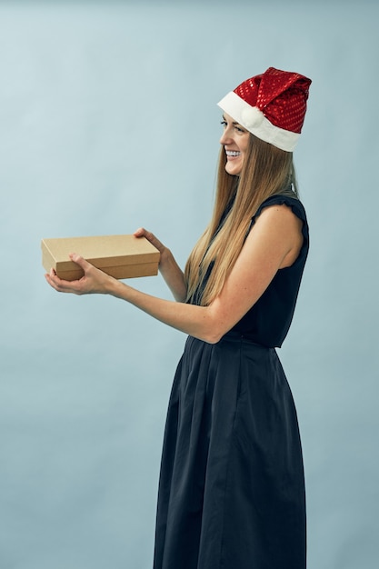 Chica con una caja de regalo en sus manos y con un sombrero de santa claus