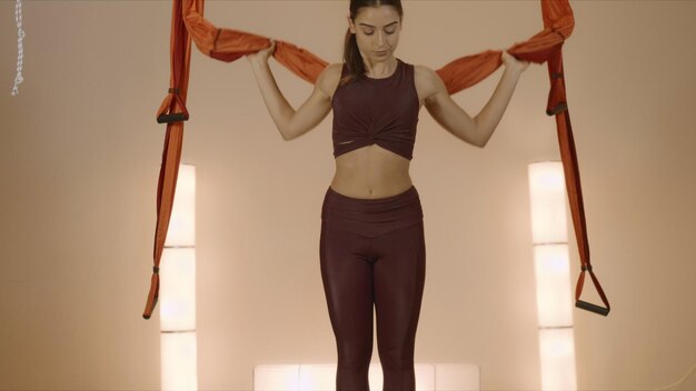 Chica calentando cuerpo en hamaca en el estudio Lady practicando yoga con mosca en el interior