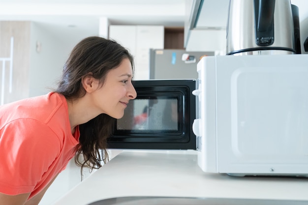 Foto chica calienta la comida en el microondas.