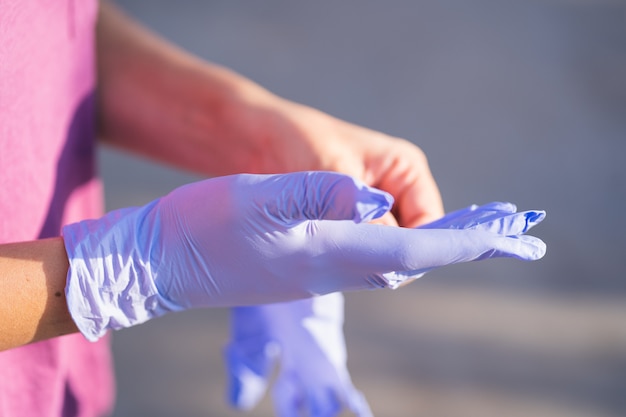 Chica en la calle sostiene guantes médicos. la niña se pondrá guantes médicos durante la pandemia de coronavirus en la calle