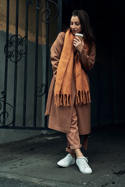 Chica de la calle con un vaso de papel desechable. Comida para llevar, pasear por la ciudad.