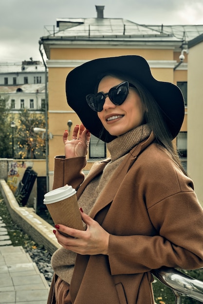 Chica de la calle con un vaso de papel desechable. Comida para llevar, pasear por la ciudad.