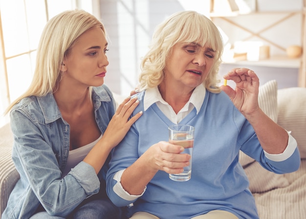 Chica calma a su triste y anciana madre que toma medicamentos