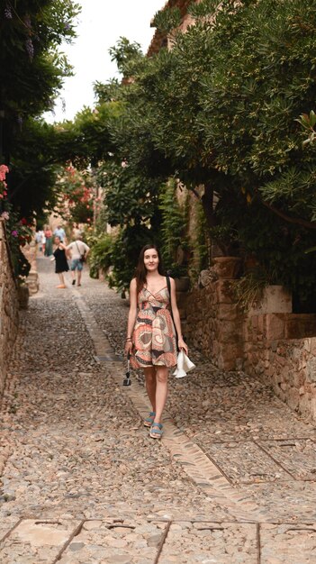 Foto una chica con una cámara de acción camina por una acogedora calle estrecha en un pueblo español