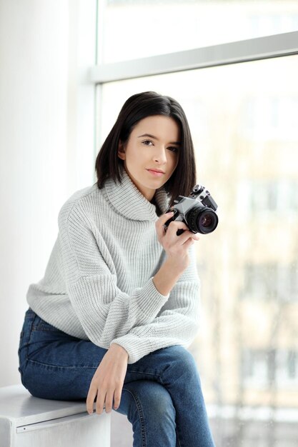 Chica con una cámara sentada junto a la ventana