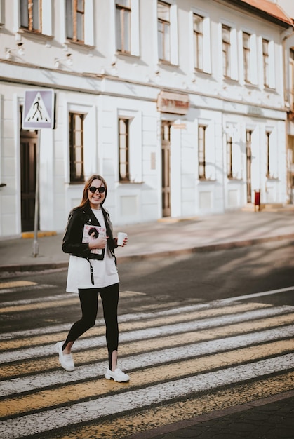 una chica camina por la ciudad. una chica con una revista. paseo por la ciudad