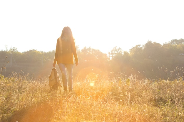 Chica caminando en el bosque de otoño a la luz del atardecer