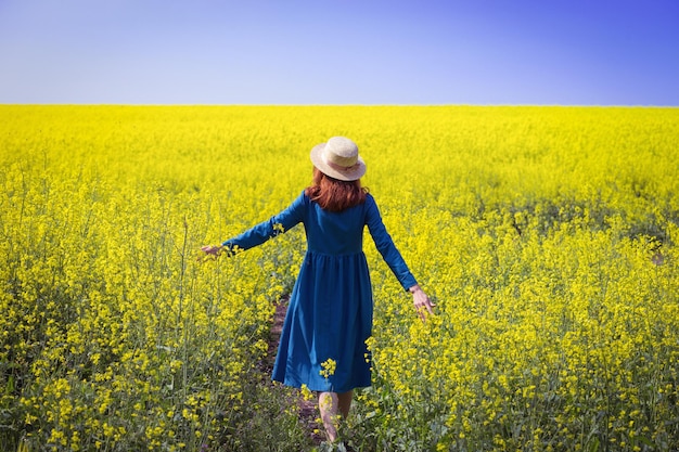 Chica caminando en un campo de colza amarilla