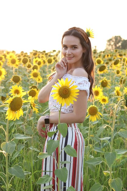 Chica caminando en un campo de girasoles con una canasta, foto de estilo rústico, campo de girasoles al atardecer. Foto de alta calidad