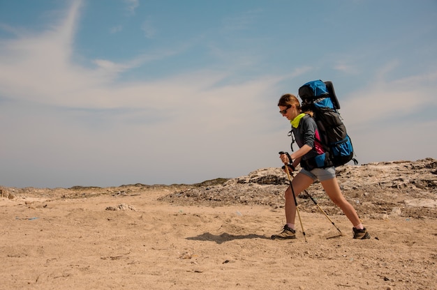 Chica caminando en el desierto con mochila de senderismo