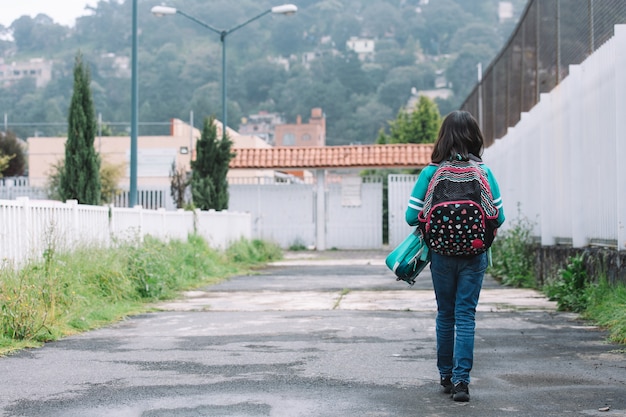 Foto chica caminando a la entrada de la escuela de regreso a la escuela