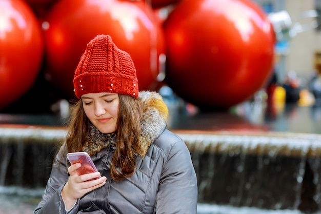 Chica caminando y enviando mensajes de texto en su teléfono inteligente