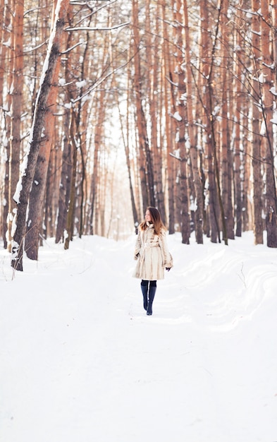 Chica caminando en la nieve. Concepto de invierno, frío y gente