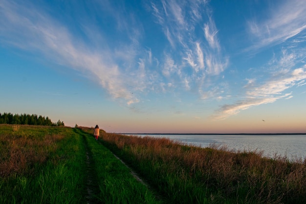 Chica caminando por la orilla del río al atardecer