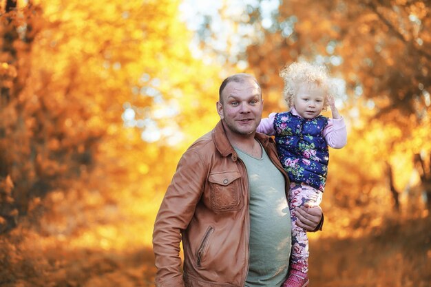 Chica caminando en el parque de otoño. Otoño en la ciudad, niña con papá a pasear. Los padres caminan con niños pequeños. Gente del parque de otoño