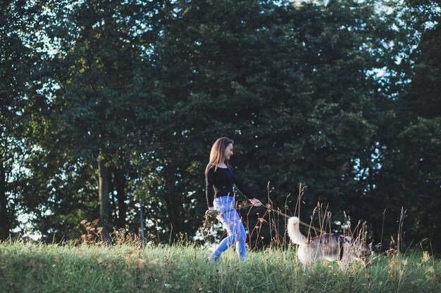 Chica caminando con perro husky