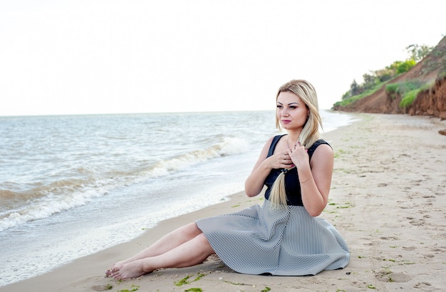 Chica caminando por la playa en tiempo nublado, con un vestido