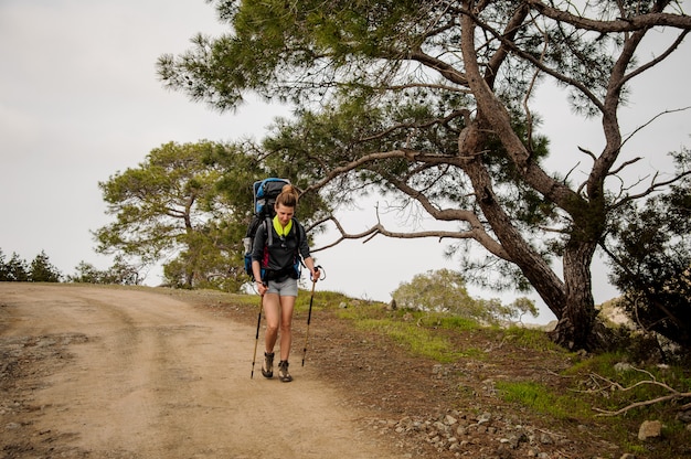 Chica caminando por el sendero con mochila de senderismo