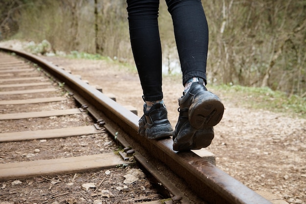 Chica caminando sobre rieles de cerca, superficie borrosa