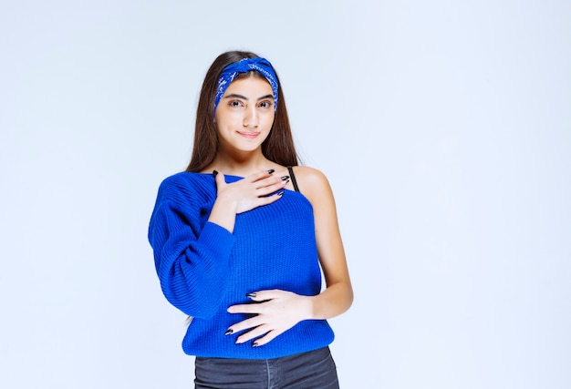 Chica con camisa azul apuntando a sí misma.