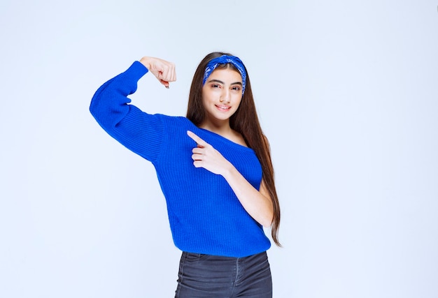 Chica con camisa azul mostrando los músculos del brazo.