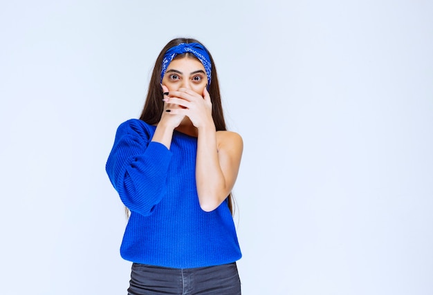 Chica con camisa azul parece asustada y aterrorizada.