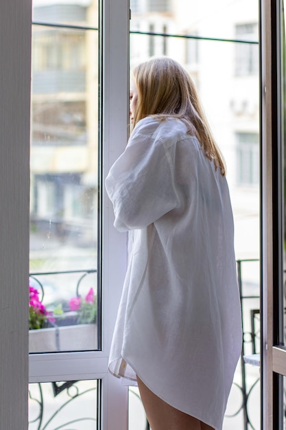 Una chica con una camisa blanca está de espaldas al balcón.