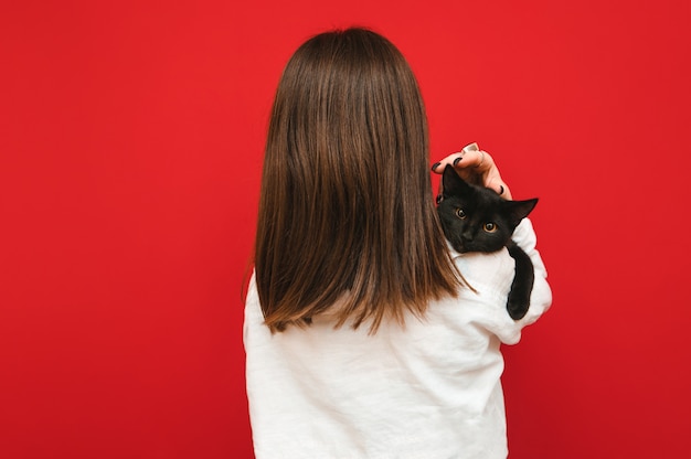 Chica con una camisa blanca con un gato negro sobre sus hombros