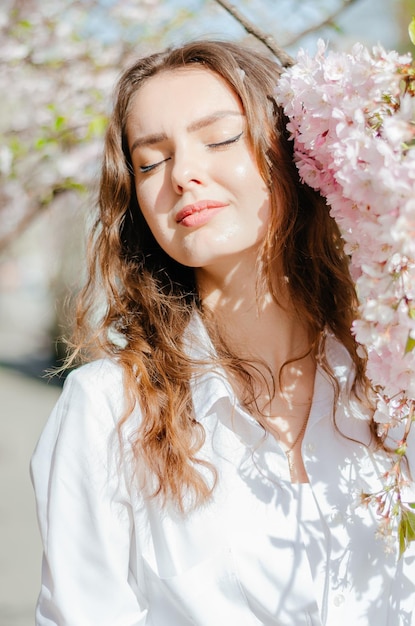 chica con una camisa blanca parada cerca de la sakura