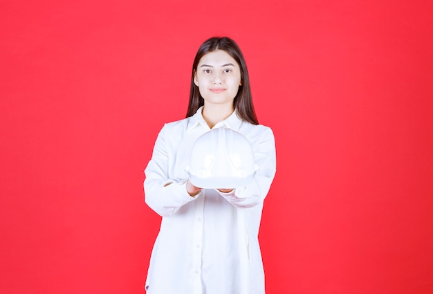 Chica con camisa blanca sosteniendo un casco blanco