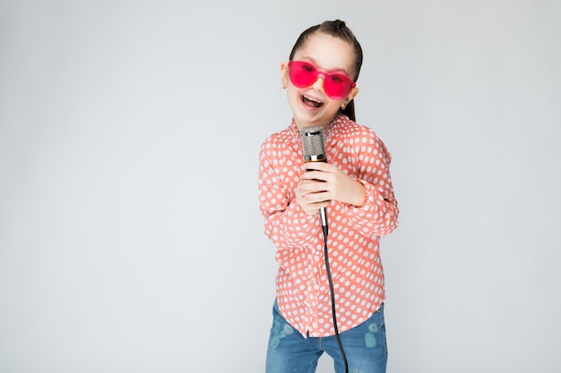 Chica en camisa naranja, gafas y blue jeans.