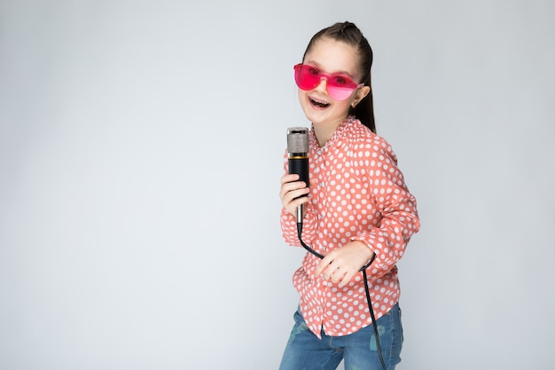 Chica en camisa naranja, gafas y jeans azul gris.