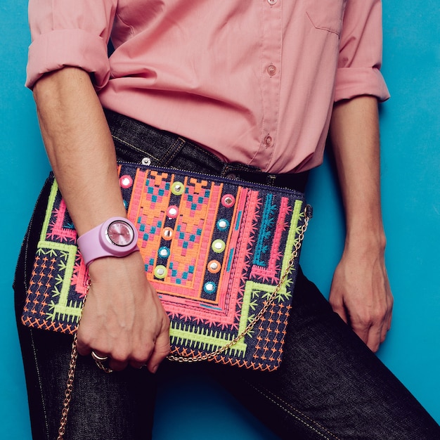 Chica en una camisa rosa y accesorios de moda. Bolso y jeans azul con estilo