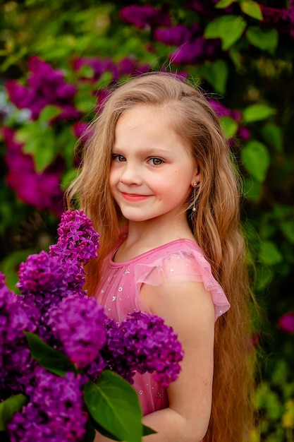 Una chica con una camisa rosa sostiene un ramo de flores moradas.