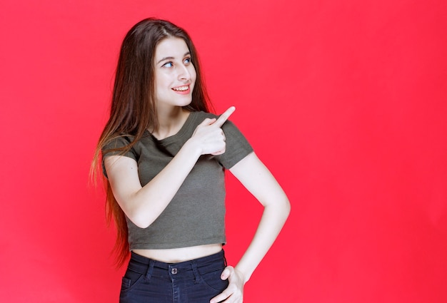 Chica con camisa verde apuntando a algo en el este.